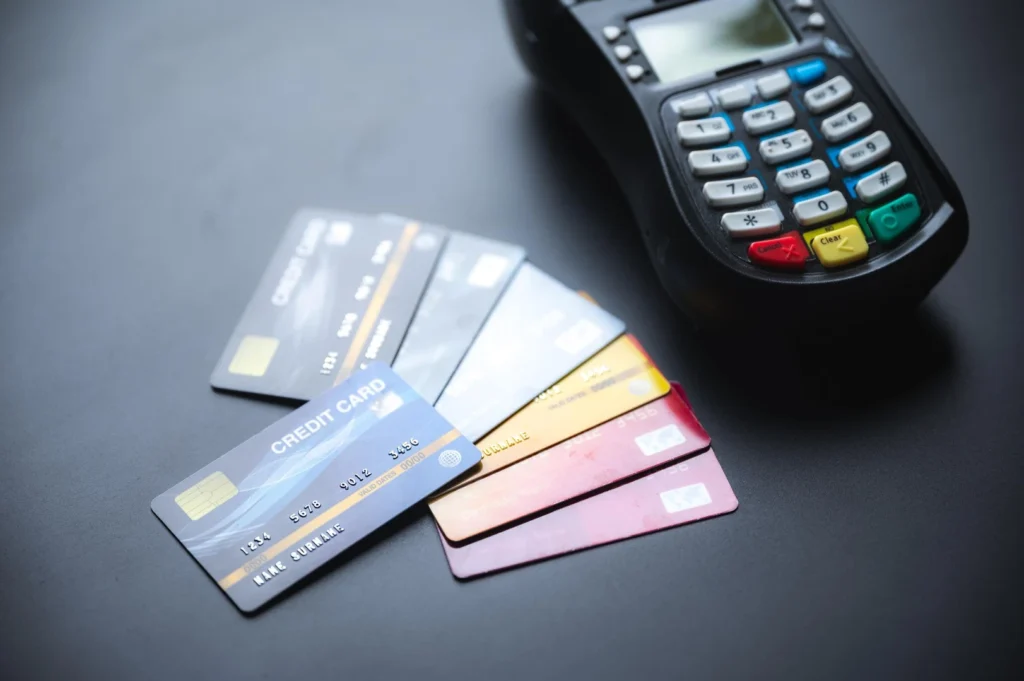 Closeup of group of credit and debit bank cards with NFC machine on a blue table used for online and plastic money transfer w